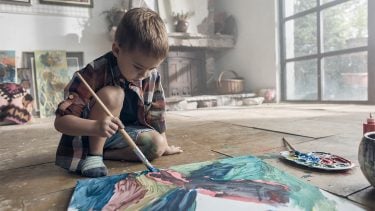 Young boy painting a canvas on the floor