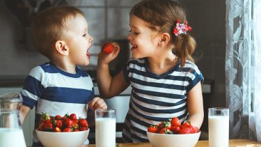 two little kids eating strawberries