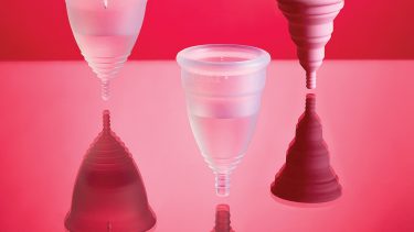 three different silicone cone-shaped menstrual cups on a pink background