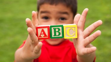 kid holding ABC wooden blocks