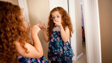 Little girl talking to herself in the mirror