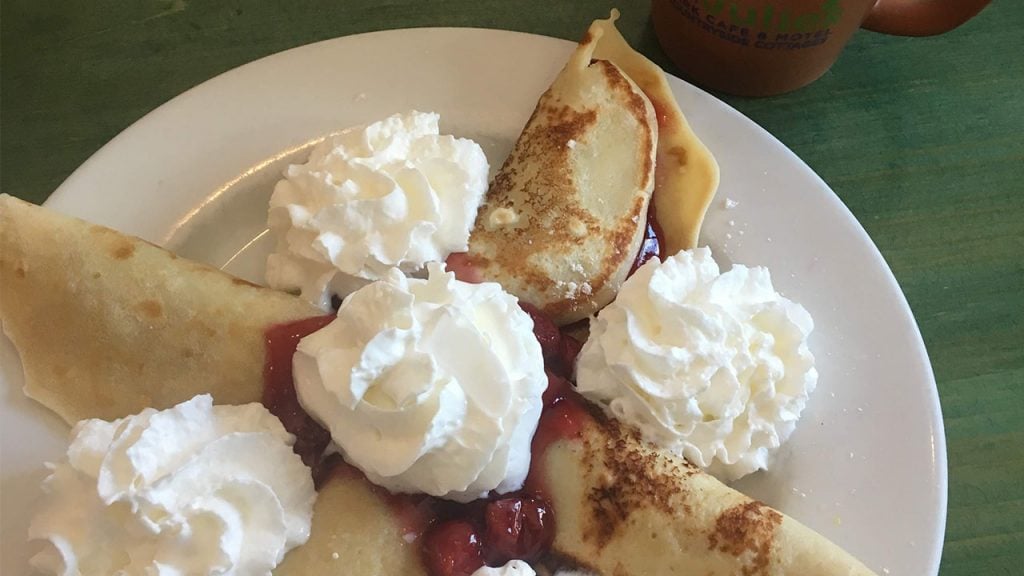 Crepes on a plate with cherry sauce of whipped cream