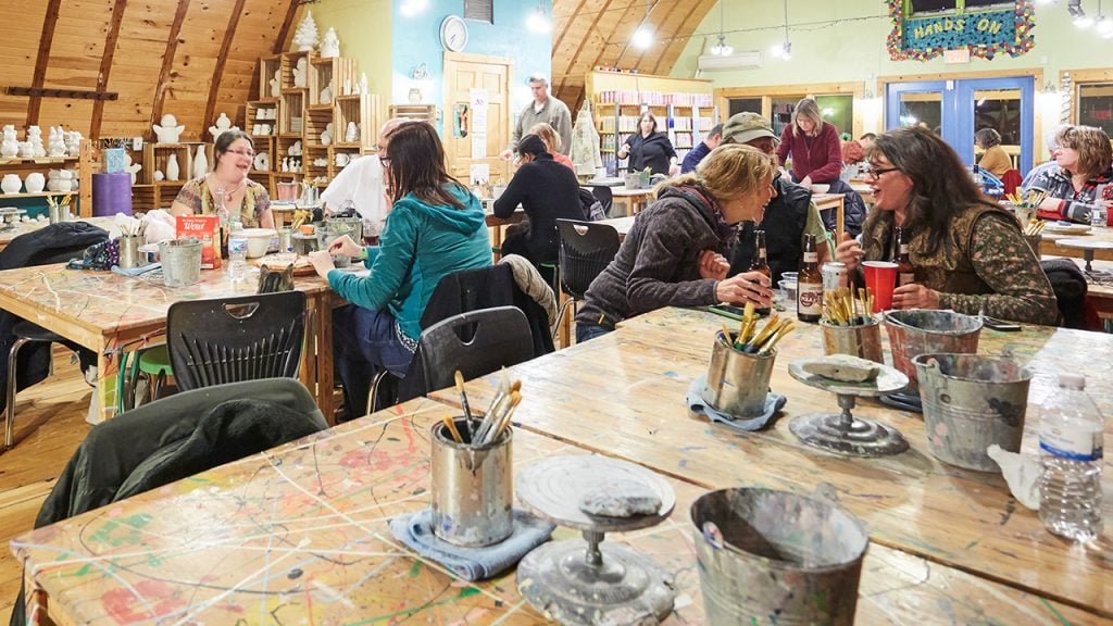 Adults sitting and making pottery and other art in barn-style setting things to do in door county
