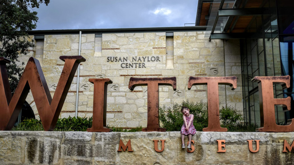 young girl sitting in front of museum signage