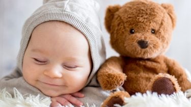 Unique baby names: Sleepy newborn rests beside a brown teddy bear