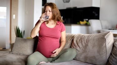 Pregnant woman drinking a glass of water thinking about fluoride during pregnancy