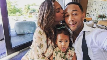 Chrissy kisses her husband on the head while they pose with their daughter Luna