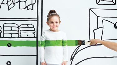 young girl standing against wall being painted green