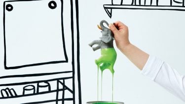 hand dipping a toy elephant in green paint