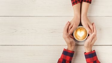 Healthy relationship: A man and woman wrap their hands around a cappuccino cup with a heart on it