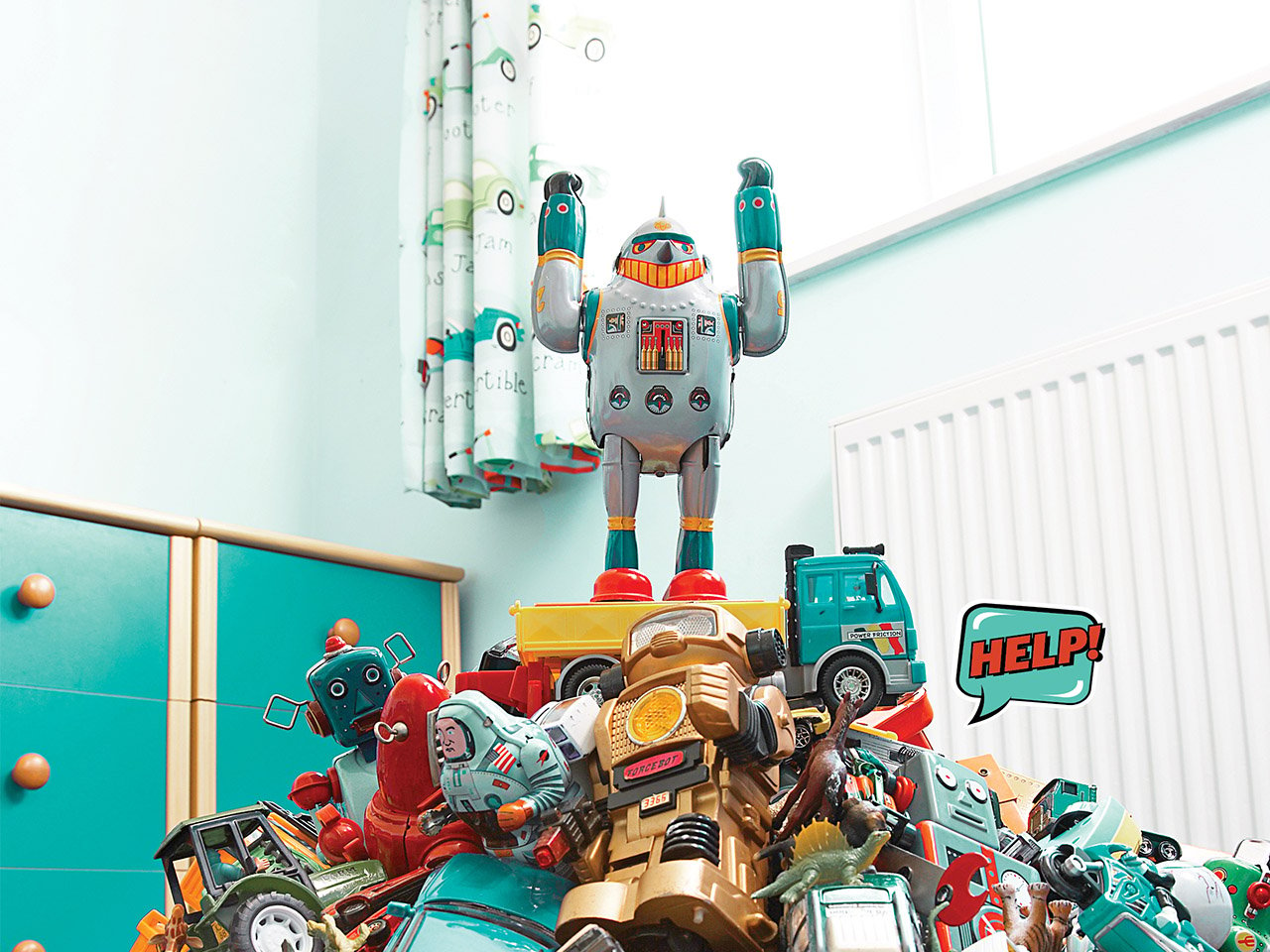 Toy robot standing on a pile of toys with his arms raised