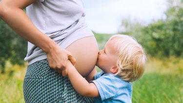 Toddler kisses mother's pregnant belly