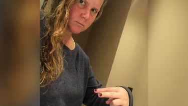 amy schumer looking angry and pointing to her breasts.