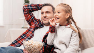 Dad and daughter eating popcorn while watching TV