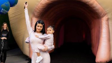 kylie jenner holding her daughter Stormi in front of the entrance to Stormi's birthday party