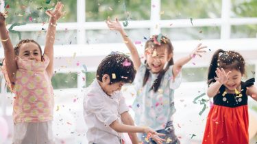 Four kids throw confetti into the air