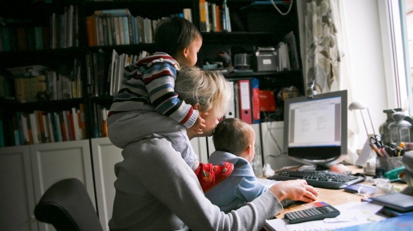 mom working at computer with kids on her lap and back