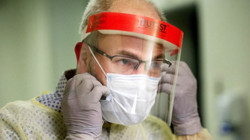 A man demonstrates how to put on a face mask and protective clothing during a tour of a COVID-19 evaluation clinic in Montreal.