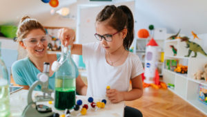 little kid doing science experiments at home with her mom