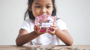 Girl holds piggy bank that holds her savings.