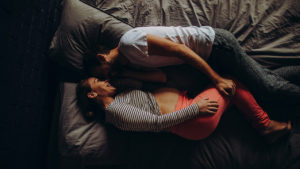 pregnant woman with partner laying in bed