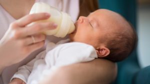 Night nurse: woman feeding a bottle of milk to a baby
