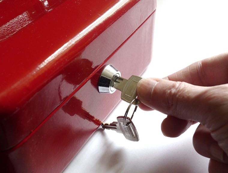 red lock box with one hand putting a key in it