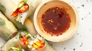 bowl of sauce surrounded by fresh spring rolls