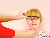 mother illustrating on her daughter how to cut bangs