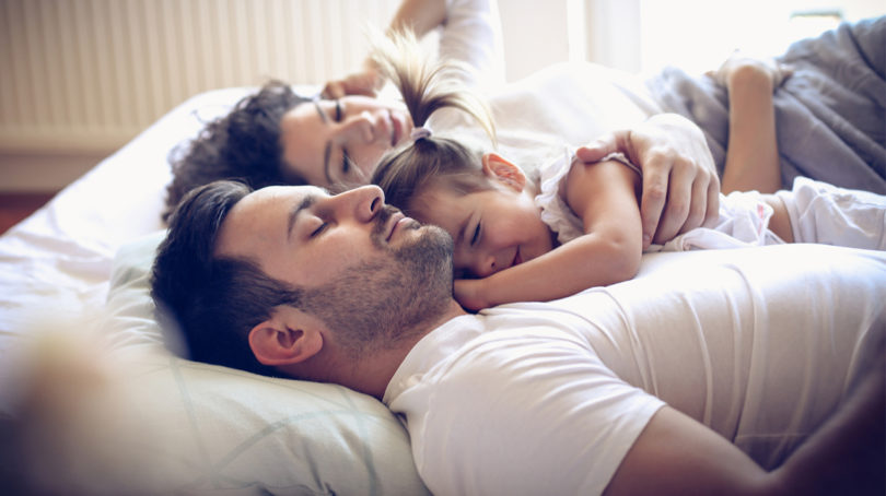  Parents allongés au lit ensemble réconfortant leur enfant 