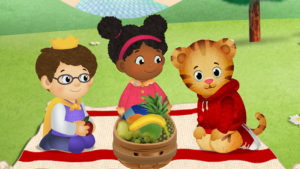 Still from Daniel Tiger's Neighbourhood showing two animated kids and an animated tiger having a picnic in the park