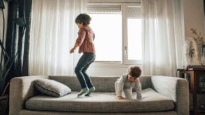 Siblings jumping on a couch