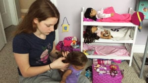 Young teen playing with doll collection
