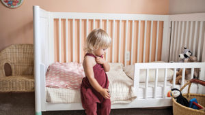 Toddler standing next to bed