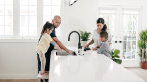 Family of four around the kitchen counter, washing hands