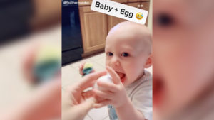 baby reaching for an egg his mom is handing him