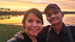 Young woman and her older father taking a selfie by a lake at sunset