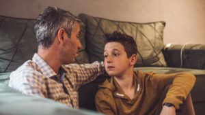 Dad sitting on the floor with son having a conversation