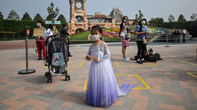 A girl wearing a face mask waits to enter the Disneyland amusement park in Shanghai on May 11, 2020. - Disneyland Shanghai reopened on May 11 to the public after being closed since January due to the COVID-19 coronavirus outbreak.