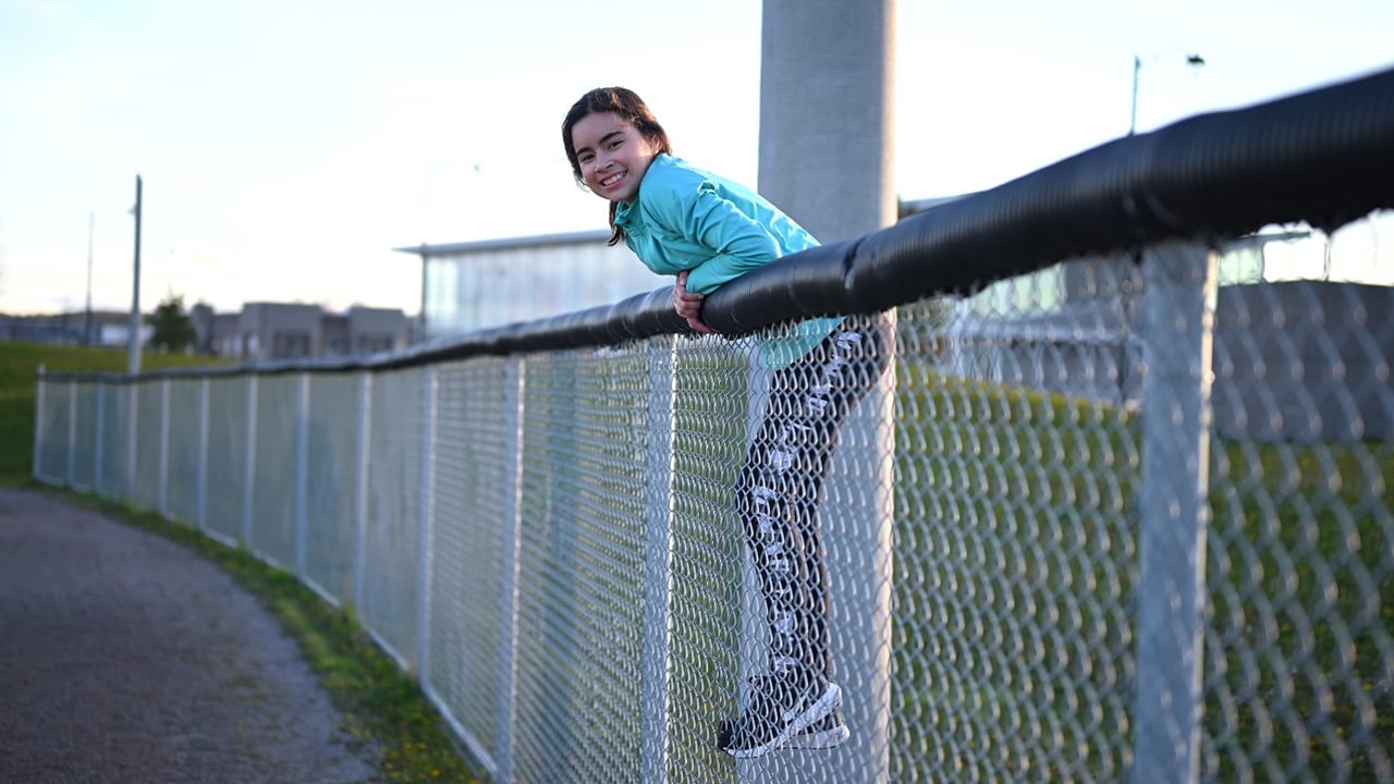 Kid leans over a fence for a photo