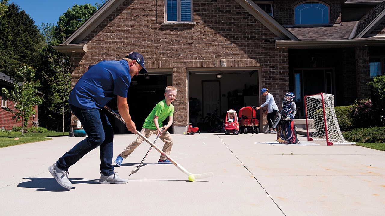 Family playing ball hockey in their driveway