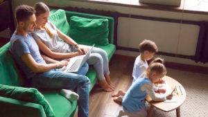 parents lounging on the couch while children colour on the coffee table