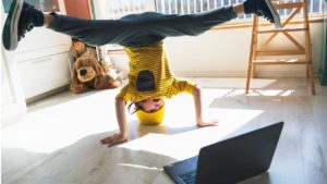 kid doing a headstand in front of a laptop