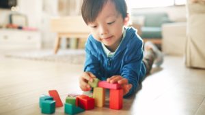 young boy playing with blocks diverse toys