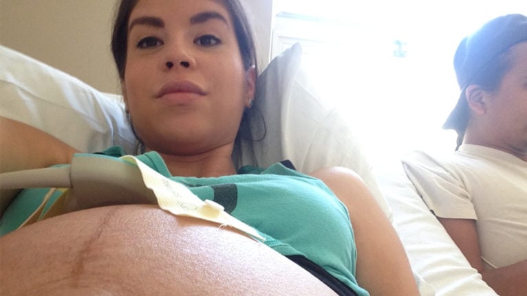 Pregnant woman laying in a hospital bed with a monitor on her baby bump