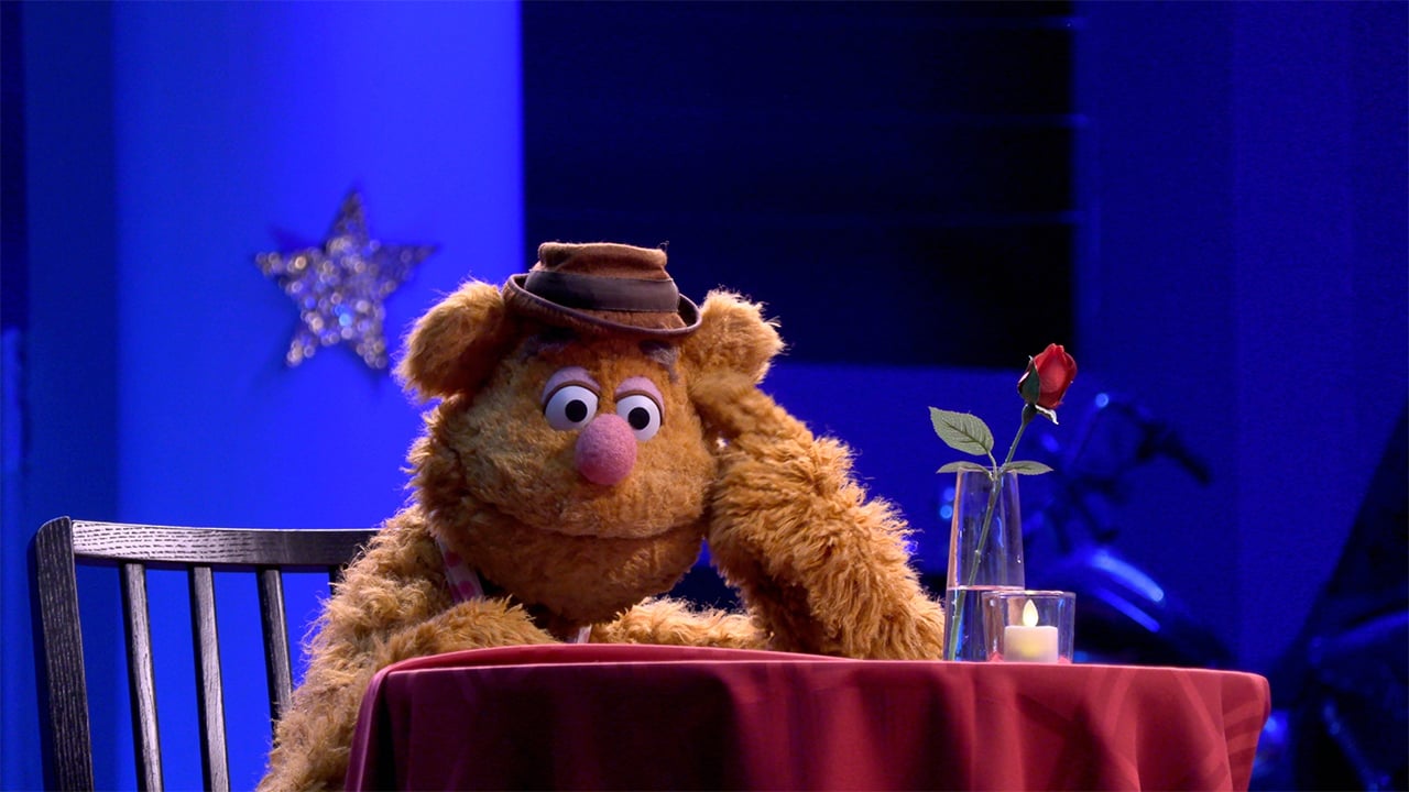 Fozzie bear the muppet sits at a table thinking