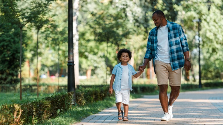 Dad and son walking through a park.