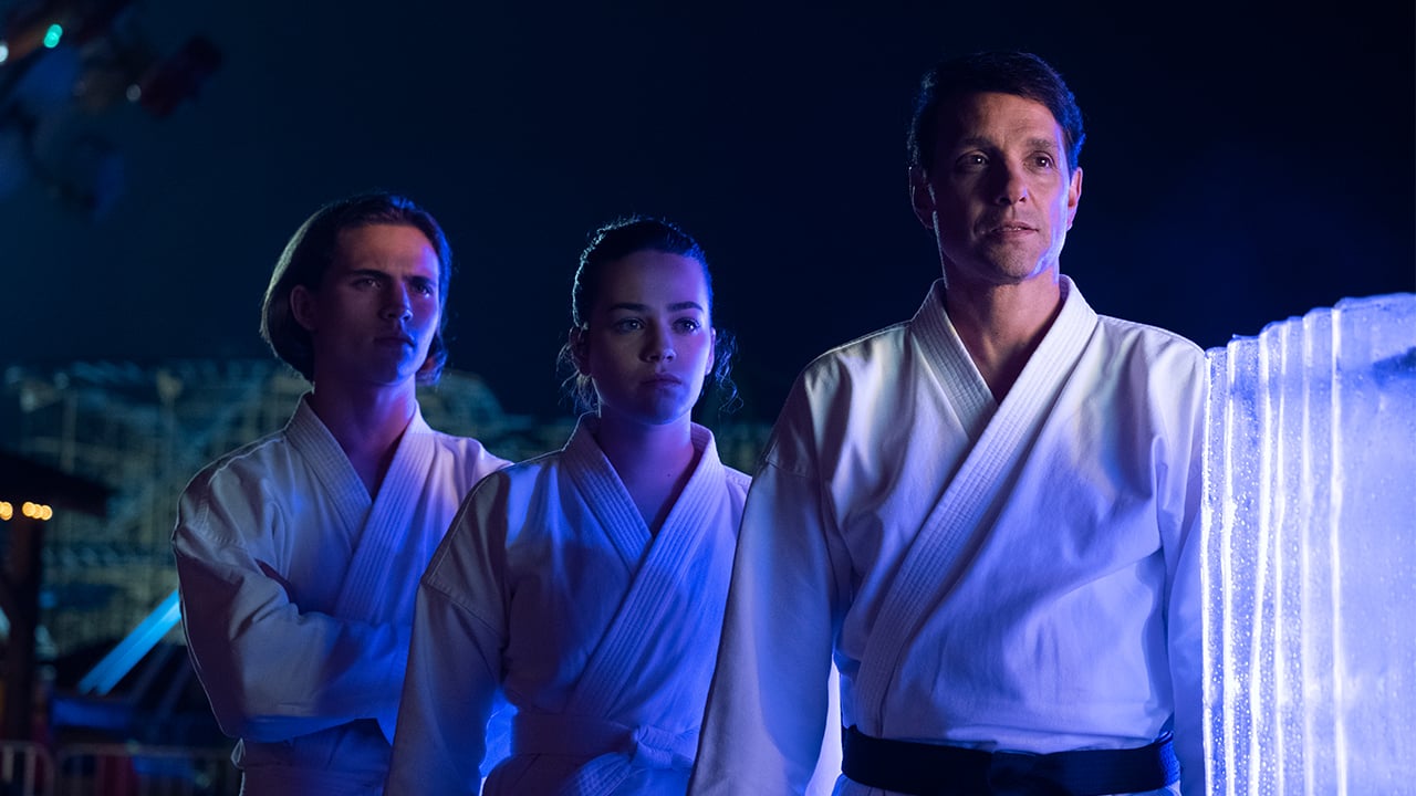 two teens stand with their karate instructor