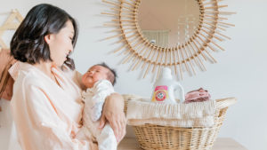 Esther Lee holding baby with laundry detergent in basket