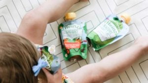 Overhead image of toddler eating Heinz By Nature puree pouches